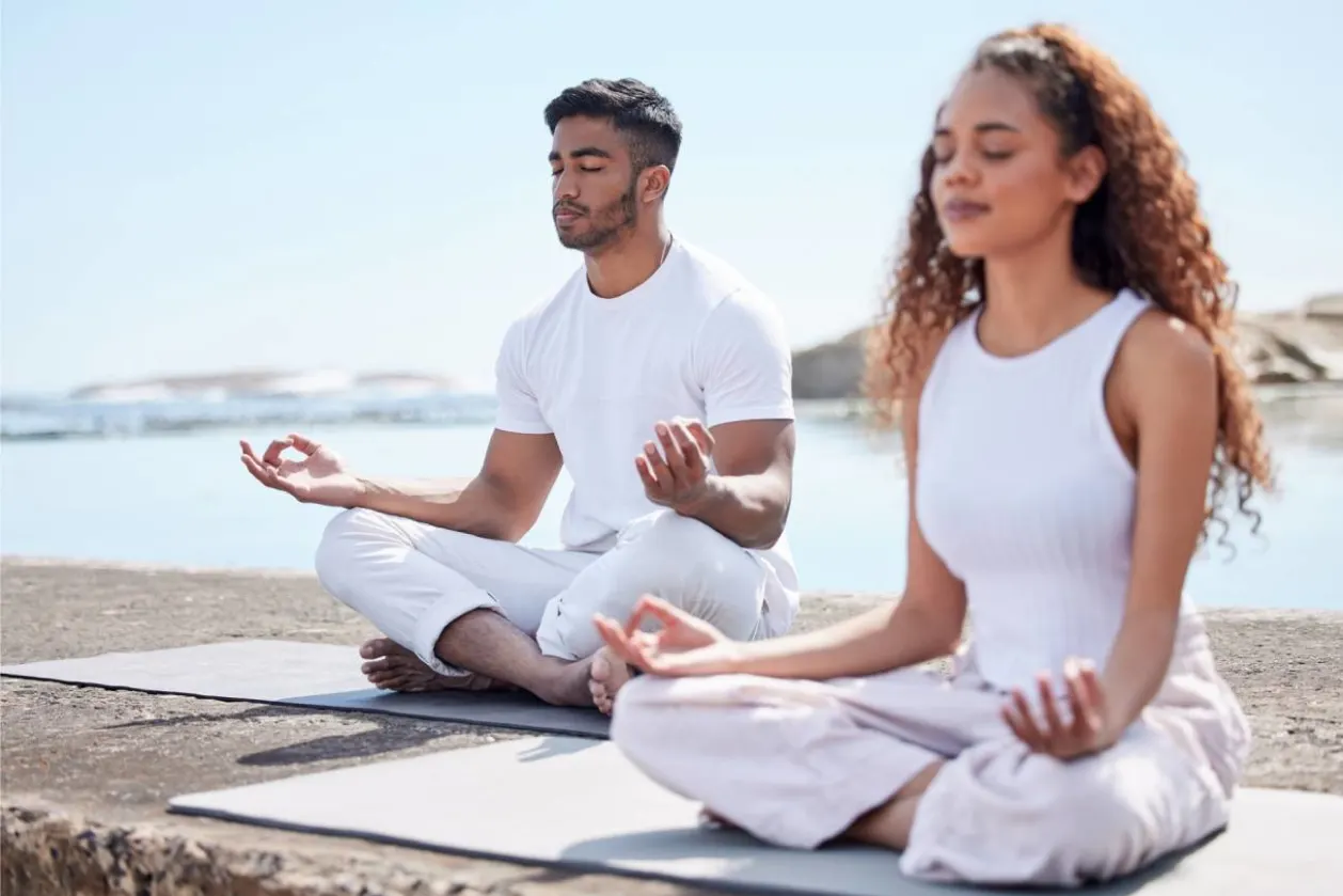 couple meditating at the beach